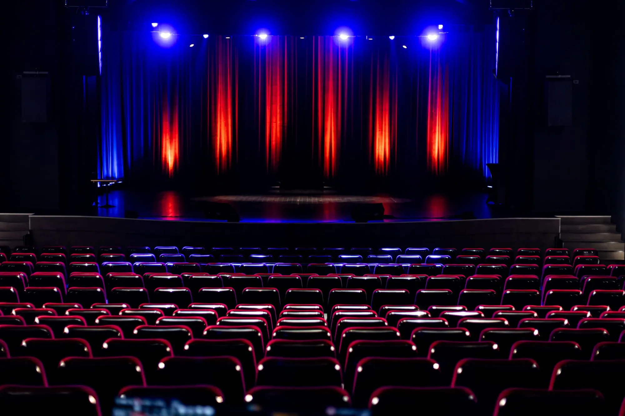 Sala widowiskowa Wąbrzeskiego Domu Kultury: czerwone fotele i scena z ekranem